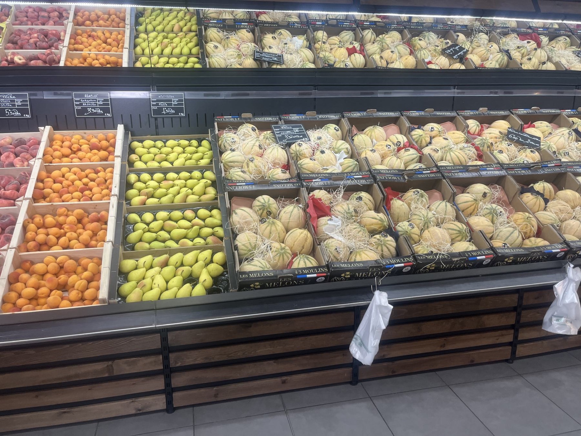 Cagettes d'abricots et de poires à côté des melons